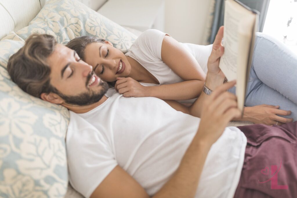A couple relaxing together on a bed with a book, close but unhurried