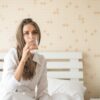 Woman drinking a glass of water in bed on a calm morning
