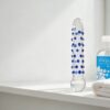 Clear textured glass dildo beside a bottle of water-based lubricant on a bathroom shelf